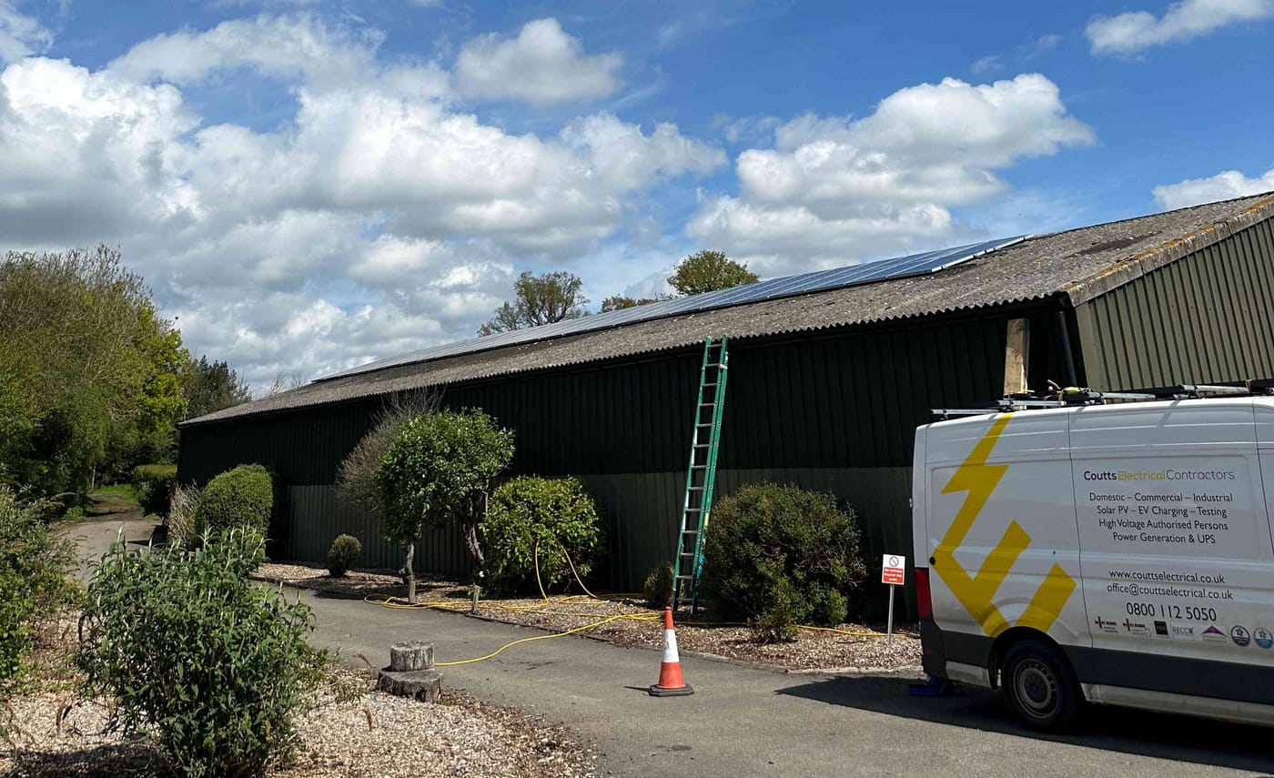 A Coutts Electrical Contractors van and ladder beside a commercial building with a roof-mounted solar array