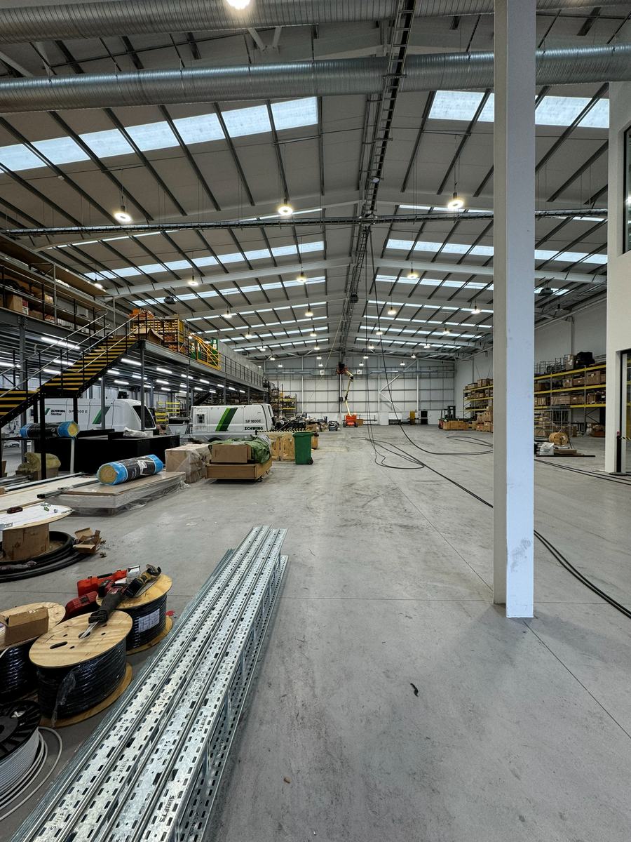 Cable ladder sections and cable drums set out on the floor of an industrial unit before first fix — photograph 19 of 25